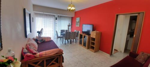 ein Wohnzimmer mit roten Wänden, einem Sofa und einem TV in der Unterkunft Depto sobre Peatonal San Martin in Mar del Plata