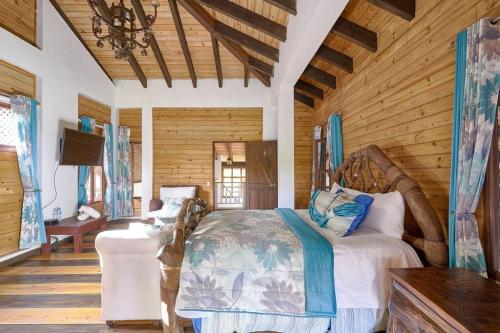 ein Schlafzimmer mit einem großen Bett in einem Zimmer mit Holzwänden in der Unterkunft Villa ines-4X4only-Jarabacoa-View-Jacuzzi-5BR in Jarabacoa