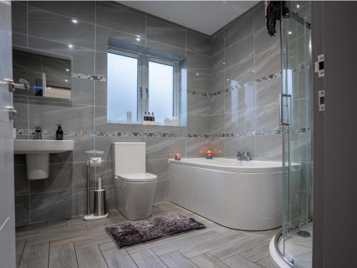 a bathroom with a tub and a toilet and a sink at Heather House , luxury holiday house in Pitlochry in Pitlochry