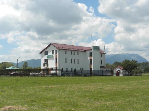 a white building with a fence in a field at Pensiunea Cetatea Craiului in Râşnov