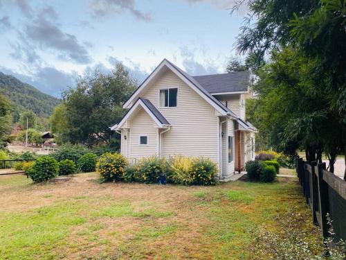 a white house with a fence in a yard at Hermosa casa a 10 minutos de Huilo Huilo in Choshuenco