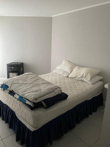 a unmade bed in a white room with at Departamento Familiar los Molles in Los Molles