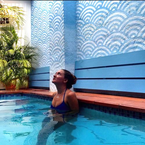 a woman is sitting in a swimming pool at La Guaca Hostel Santa Marta in Santa Marta