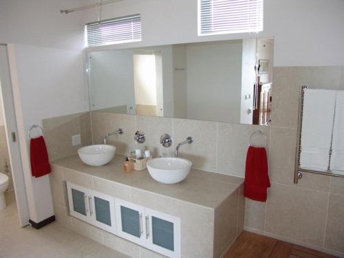 La salle de bains est pourvue de 2 lavabos et d'un grand miroir. dans l'établissement Crayfish Lodge Sea & Country Guest House, à Gansbaai