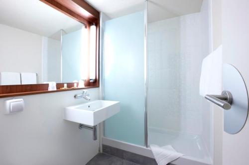 a bathroom with a shower, sink, and mirror at Campanile Lille Euralille in Lille