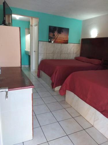 1 dormitorio con 2 camas con sábanas rojas y paredes azules en Hotel Duve Coral, en Loreto