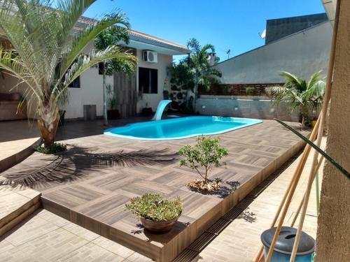 un patio trasero con piscina y palmeras en Edicula com um quarto banheiro e piscina e lazer, en Foz do Iguaçu