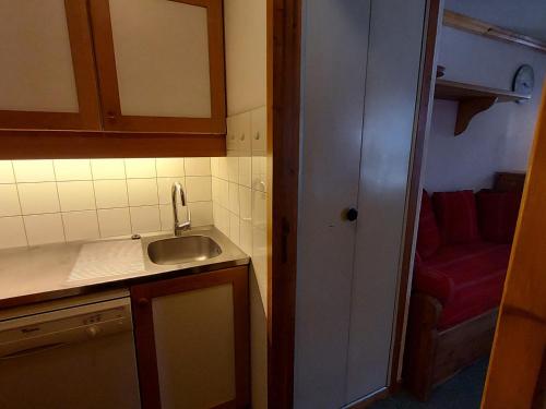 eine kleine Küche mit einem Waschbecken und einem roten Sofa in der Unterkunft Appartement Valmorel, 1 pièce, 4 personnes - FR-1-356-391 in Les Avanchers