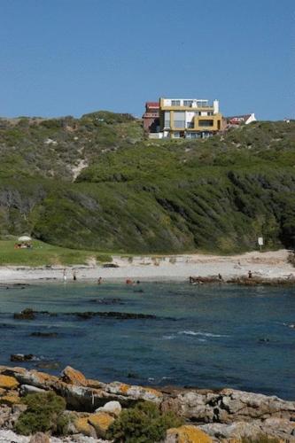 a house on top of a hill next to a beach at Crayfish Lodge Sea & Country Guest House in Gansbaai