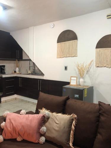 a living room with a brown couch and a kitchen at Loft Bonhomia with parking 7min to downtown in Guanajuato
