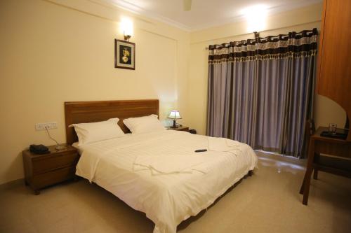 Un dormitorio con una gran cama blanca y una ventana en The Lounge Business Hotel, en Bangalore