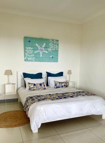 a bedroom with a large white bed with a picture on the wall at Frangipanier 2 bedrooms Sea view Penthouse in Trou aux Biches