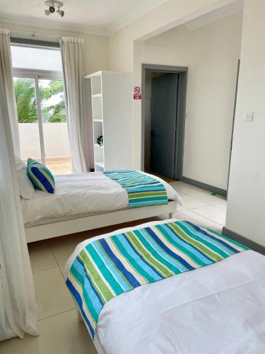 two beds in a room with a window at Frangipanier 2 bedrooms Sea view Penthouse in Trou aux Biches