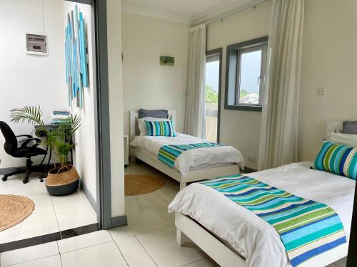 a bedroom with two beds and a window at Frangipanier 2 bedrooms Sea view Penthouse in Trou aux Biches