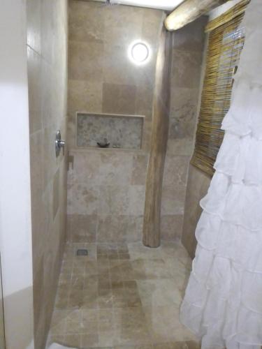 a bathroom with a shower with a stone wall at Chiibal in Tulum