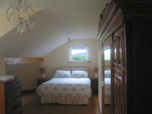 a bedroom with a bed and a window and a chandelier at White Hill Country House B&B in Castleblayney