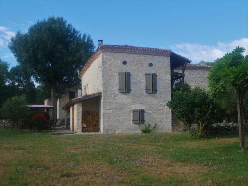 a stone house with two windows on a field at Domaine de Fangal, Pgeonnier 2p, maison 8p - piscine 25m - gîtes climatisés in Septfonds