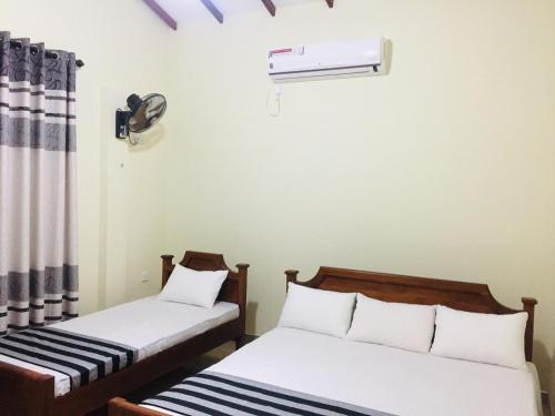 two beds in a room with a air conditioner at Sweet Home Tourist Rest, Cooking Classes & Tours in Anuradhapura