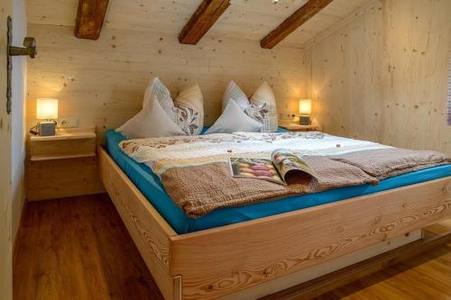 duże łóżko w drewnianym pokoju z 2 lampami w obiekcie Kaltbachlehen Ferienwohnungen w mieście Ramsau