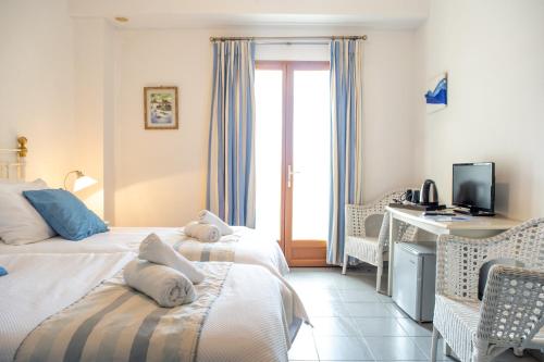 a bedroom with two beds and a desk with a computer at Lagou Raxi Country Hotel in Lafkos
