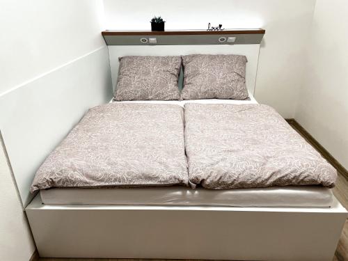 a white bed with two pillows on top of it at Apartmán Rajecké Teplice in Žilina