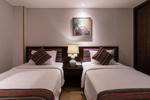 a hotel room with two beds and a lamp at Au Lac Legend Hotel in Ho Chi Minh City