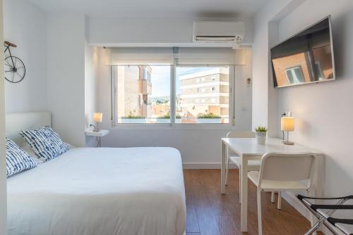 1 dormitorio con cama, mesa y ventana en LU&CIA Malagueta 9, en Málaga
