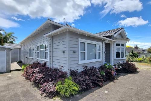 a white house with flowers in front of it at Central Auckland 5-Bedroom Villa with Free Parking in Auckland