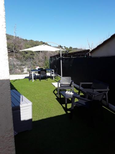 un patio con mesa, sillas y sombrilla en F1 avec un espace jardin, en Gattières