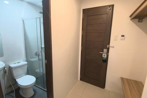 a bathroom with a toilet and a wooden door at Mango Suites in Tuguegarao City