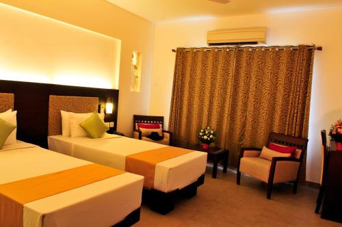 a hotel room with two beds and a chair at Copper Folia in Kozhikode