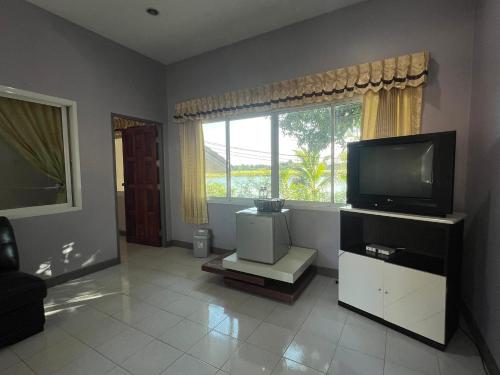 a living room with a television and a window at ทุ่งดินดำ Farm Stay in Ban Kho Wang