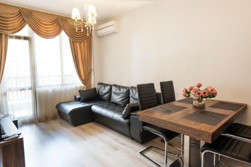 a living room with a black leather couch and a wooden table at The Green Paradise Apartments in Primorsko