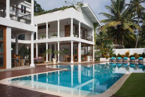 a hotel with a swimming pool in front of a building at Ginger Palm Villa in Hiriketiya