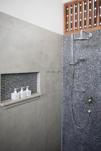 a bathroom with a shower with black tiles at Ginger Palm Villa in Hiriketiya