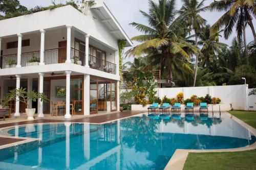 a villa with a swimming pool in front of a house at Ginger Palm Villa in Hiriketiya
