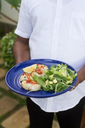a person holding a plate of food with a salad at Ginger Palm Villa in Hiriketiya