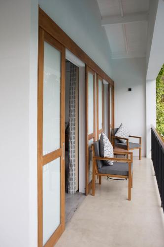 a room with a door and chairs on a balcony at Ginger Palm Villa in Hiriketiya