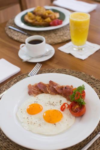a plate of eggs and bacon and a glass of orange juice at Ginger Palm Villa in Hiriketiya