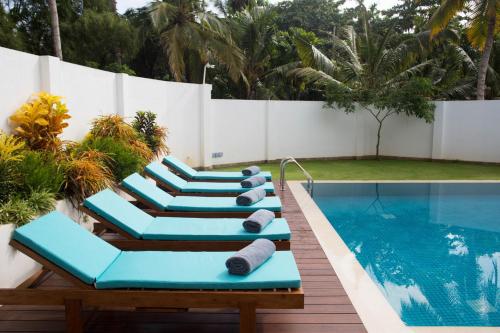 a row of lounge chairs next to a swimming pool at Ginger Palm Villa in Hiriketiya
