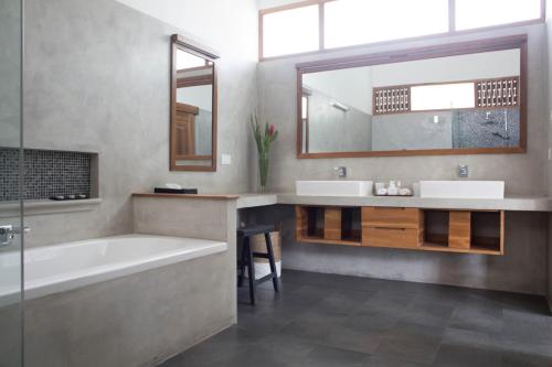 a bathroom with two sinks and a tub and a mirror at Ginger Palm Villa in Hiriketiya