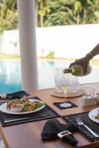 a person is pouring a glass of wine on a table at Ginger Palm Villa in Hiriketiya