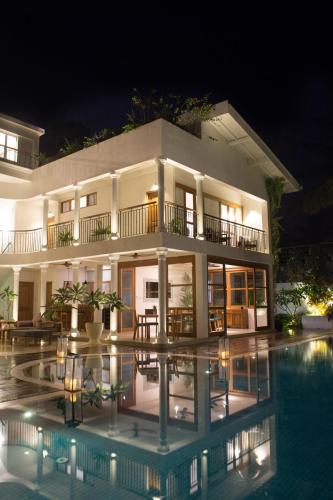 a building with a pool in front of it at night at Ginger Palm Villa in Hiriketiya