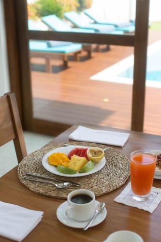 a plate of fruit on a table with a cup of coffee at Ginger Palm Villa in Hiriketiya