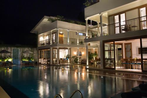 a building with a swimming pool at night at Ginger Palm Villa in Hiriketiya