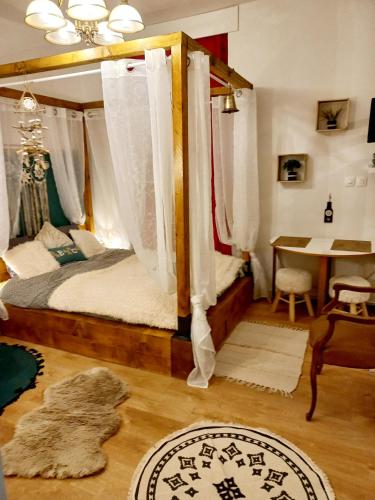 a bedroom with a canopy bed and a table at STUDIO DU VOYAGE GARE D AURAY in Brech