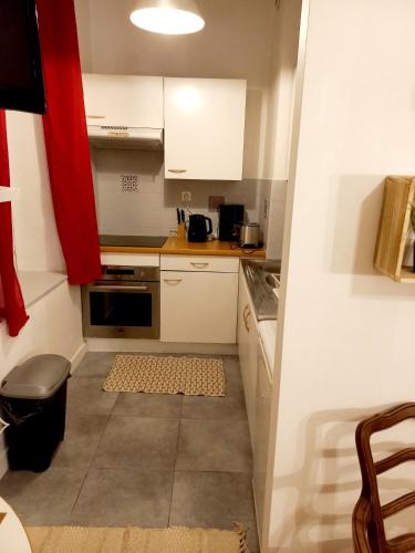 a small kitchen with white cabinets and a red curtain at STUDIO DU VOYAGE GARE D AURAY in Brech