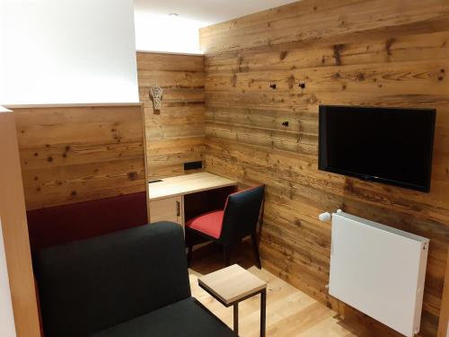 a room with a desk and a tv on a wooden wall at Landgasthof Lusenblick in Grafenau