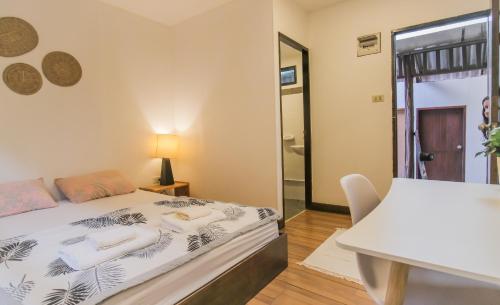 a bedroom with a bed and a table and a mirror at BOHO Hostel in Ko Lanta