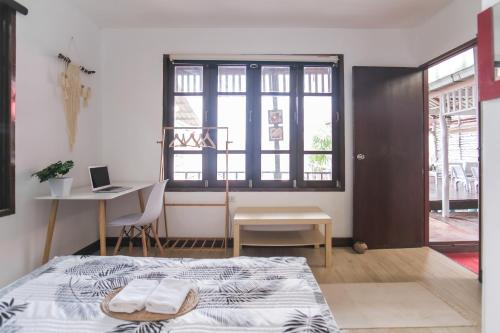 a bedroom with a bed and a desk and a window at BOHO Hostel in Ko Lanta